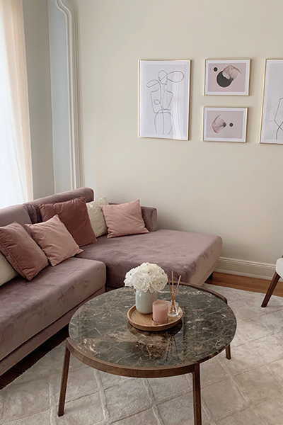 Photo d'un canapé TYME trois places en velours rose bonbon, installé dans un salon à la décoration neutre et chaleureuse